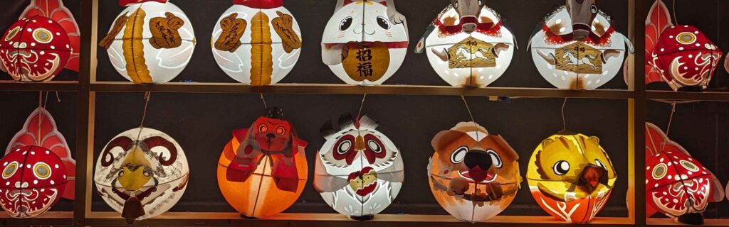 Wall of small round paper lanterns shaped like animals and characters