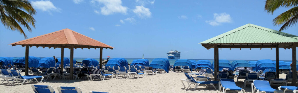 A beach lined with blue cabanas and lounge chairs facing the ocean