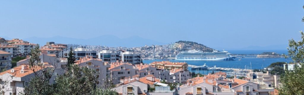 A cruise ship docked near Kusadasi with the town and harbor in view