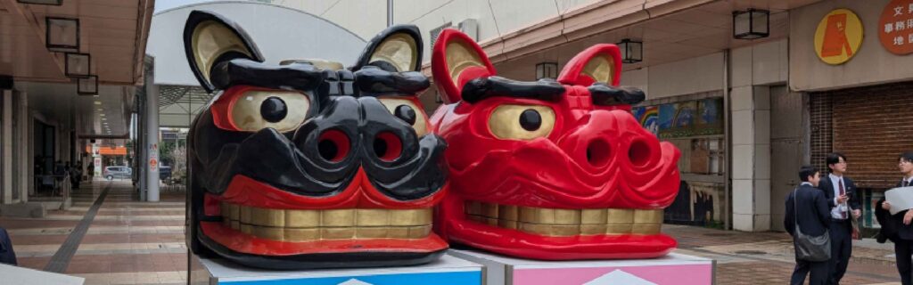 Two large lion dance masks displayed in a covered walkway