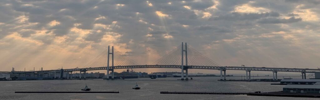 Yokohama Bay Bridge under dramatic clouds at sunrise rays