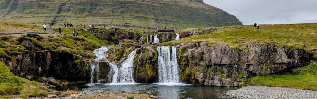 Panoramic view of Kirkjufellsfoss waterfall and grassy cliffs