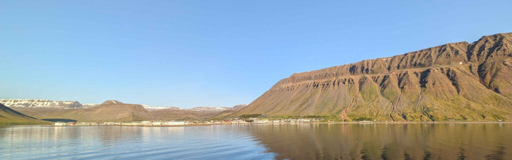 Wide panoramic view of Isafjordur nestled beneath massive mountains
