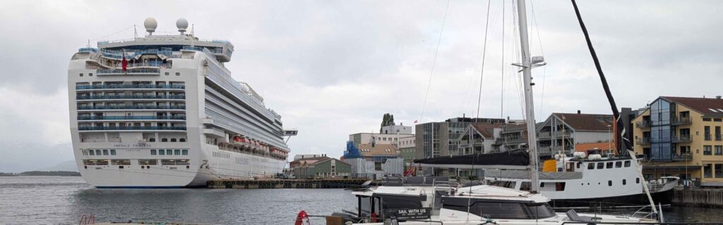 A large cruise ship docked beside sailboats in Molde harbor