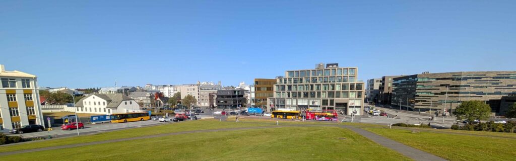 Modern Reykjavik cityscape showing a large green park area surrounded by contemporary buildings and colorful buses