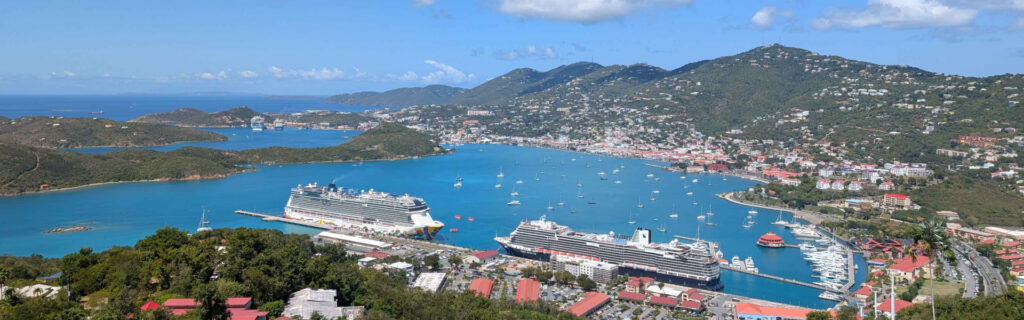 Wide panoramic view of St Thomas harbor with two cruise ships and surrounding town