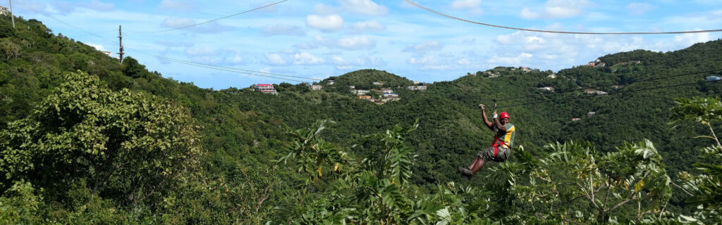 Zip line guide soaring over green canopy in Tortola