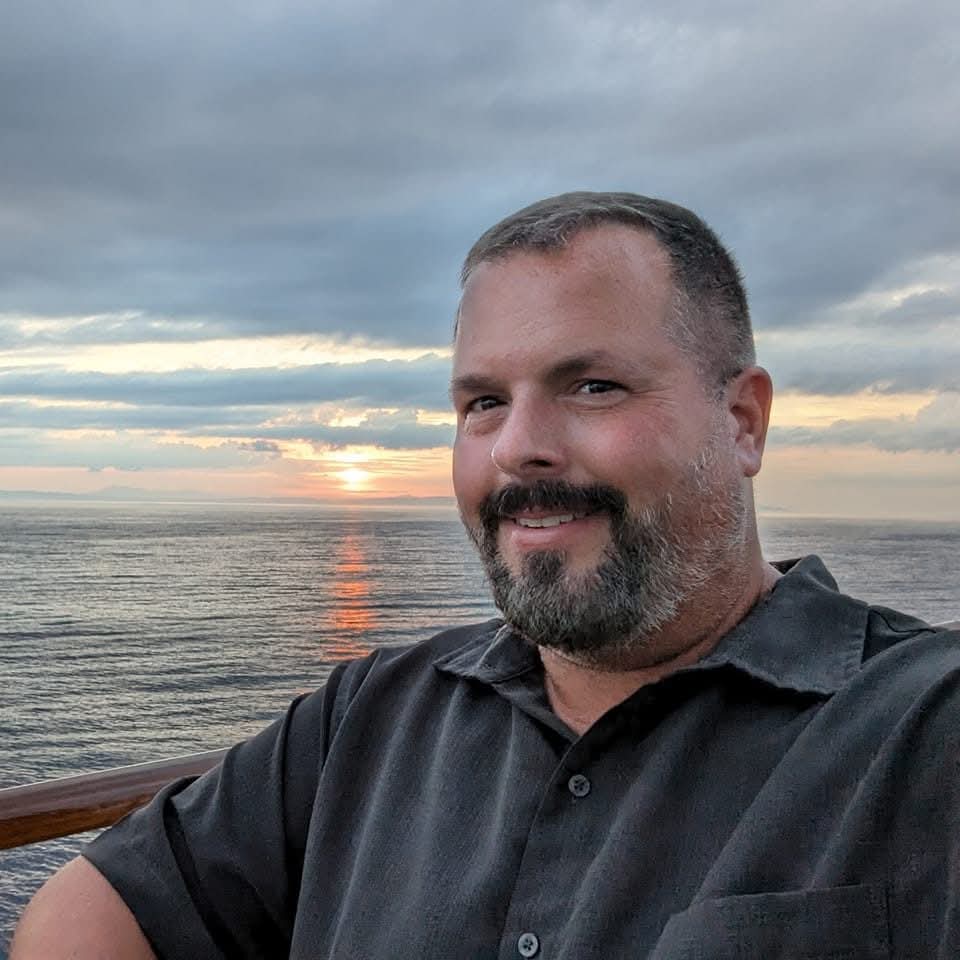 Portrait of Jeremy Perdue smiling at sunset, representing clarity and empathy in leadership.