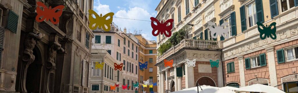 Colorful butterfly decorations strung across a narrow street in Genoa old town