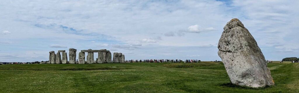 Stonehenge stone circle with a prominent leaning stone in the foreground under a wide sky