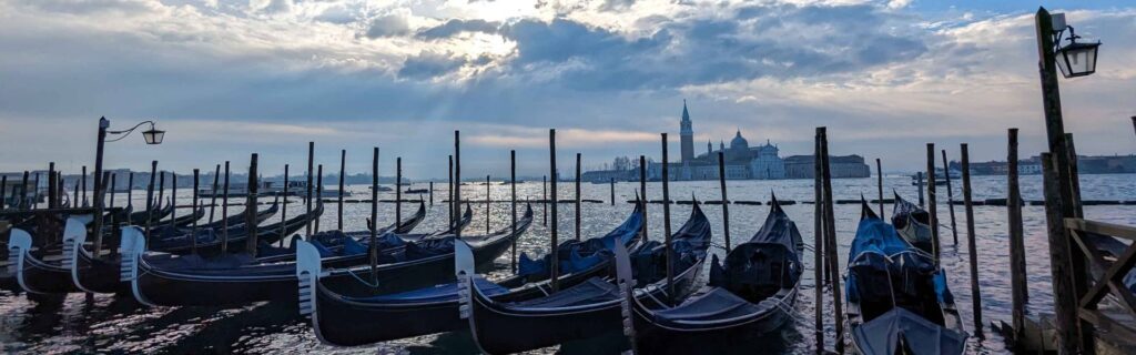 Gondolas moored on the lagoon with San Giorgio Maggiore in the distance in Venice