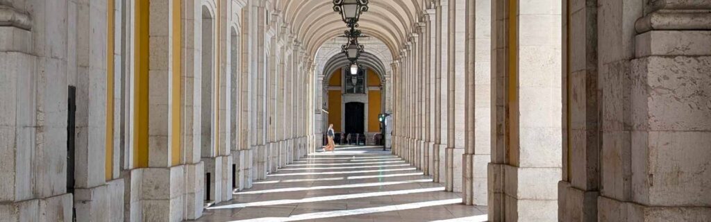 Arched colonnade of Praça do Comércio leading toward Arco da Rua Augusta in Lisbon morning glow