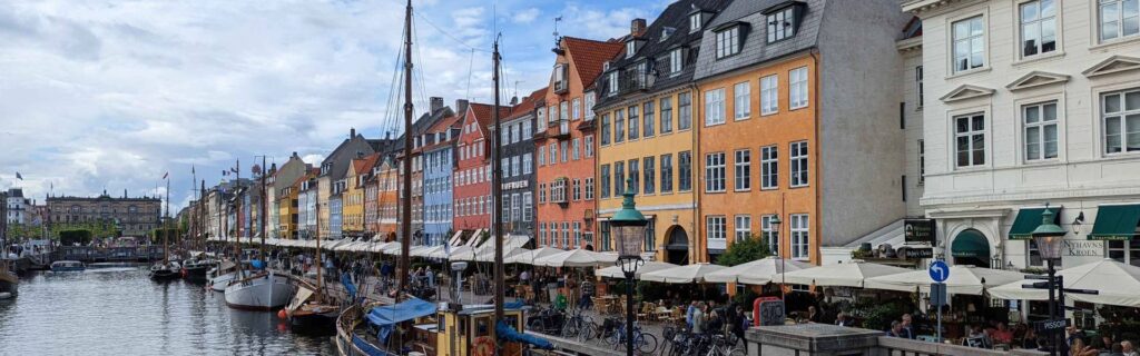 Colorful harborfront buildings and canal boats along Nyhavn in Copenhagen Denmark.