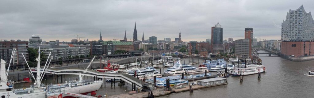 Hamburg skyline viewed from Cruise Center HafenCity with the Elbphilharmonie and harbor under rainy July skies.